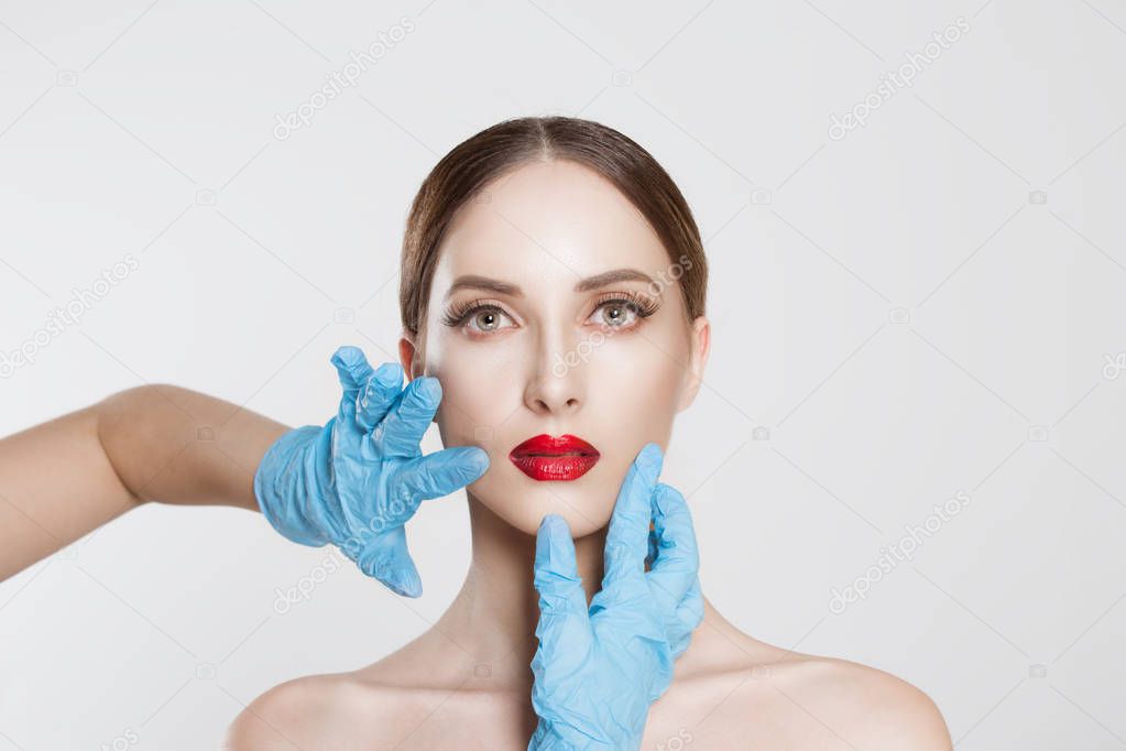 Lips surgery. wish to be beautiful need for beauty. Closeup portrait doctor hands with gloves touching woman face chin lips want to change her form do plastic surgery.  image horizontal studio shot