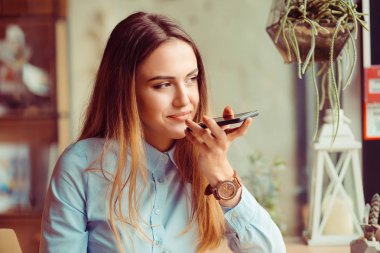 Manhattan New York'ta bir trendy rahat kafe kafede oturan telefonun ses tanıma kullanan bir kız portresi