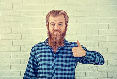 Başparmak yukarıya hareketi el parmakları ile gösterilen neşeli sarışın sakallı yakışıklı beyaz tuğla duvar arka plan izole. Tonlu görüntü retro tarzı bin yıllık adam. Olumlu insan duygu yüz ifadesi