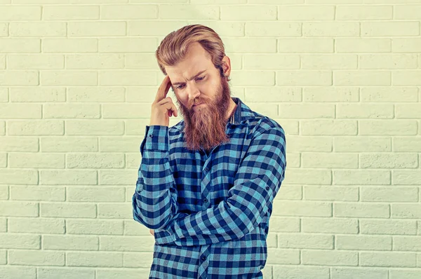 A pensar. Retrato de um homem preocupado casual homem camisa azul olhando para baixo wards isolado fundo da parede de tijolo branco. Imagem em tons amarelos, horizontal. Emoção humana negativa, expressão facial — Fotografia de Stock