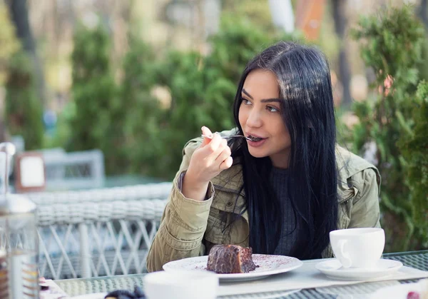 Primer plano retrato de una joven comiendo postre chocolate helado cuchara lamiendo al aire libre en verano terraza cafetería. Vista lateral — Foto de Stock