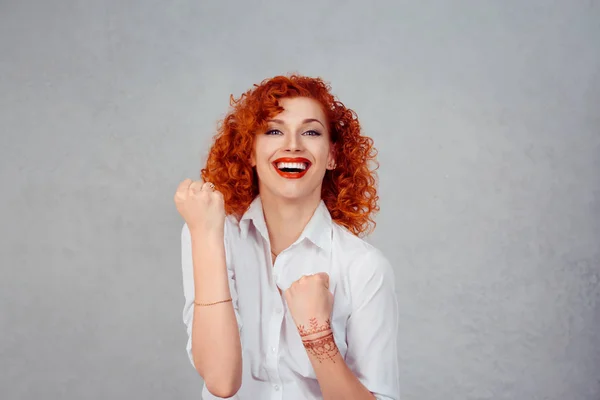 Vencedor. Feliz ruiva encaracolado mulher de negócios exulta bombeamento punhos extático celebra sucesso olhando para cima isolado no fundo da parede cinza com espaço de cópia — Fotografia de Stock