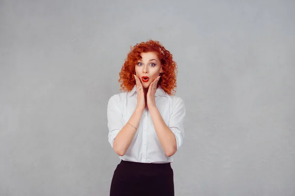 Wow. Close-up portret jonge vrouw mooi meisje met krullend rood haar, op zoek naar enthousiast bedrijf haar mond opende, handen op de wangen, geïsoleerd grijze muur. Geschokt verrast bedwelmd. Positieve menselijke emotie — Stockfoto