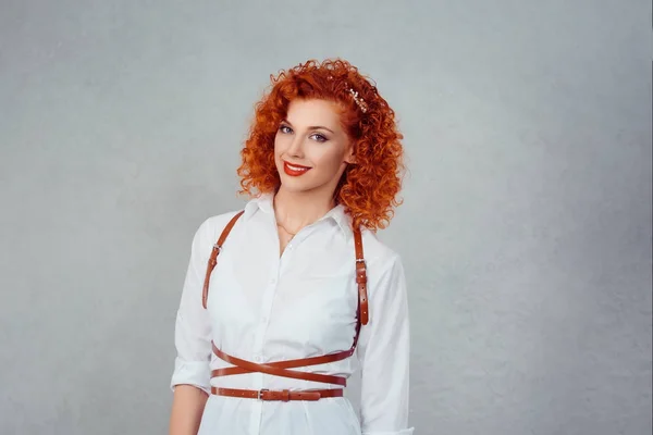 Uma mulher de negócios feliz a sorrir. Menina alegre no desgaste formal camisa branca ruiva cabeça ruiva cabelo encaracolado olhando para você sorrir no rosto isolado na parede de fundo cinza. Emoções positivas, expressão humana — Fotografia de Stock