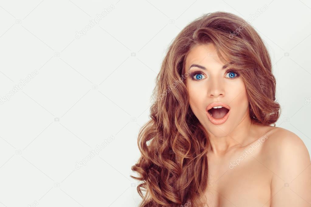 Wow. Close up portrait young woman beautiful girl with long brown curly hair blue eyes looking excited mouth opened isolated  white background wall. Shocked surprised stunned. Positive human emotion