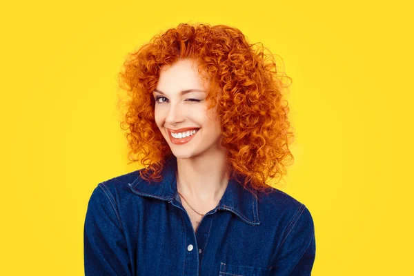 A piscar. Closeup mulher ruiva cabelo encaracolado sorrindo olho piscando para você câmera isolada no fundo amarelo. Vida feliz imagens, felicidade — Fotografia de Stock