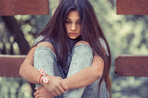 Lonely young girl embracing knees — Stock Photo, Image