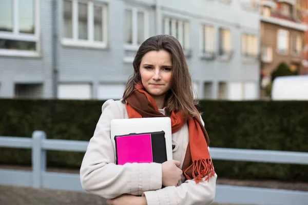 Unhappy student. Frustrated woman teenage girl holding books laptop in hand looking at camera