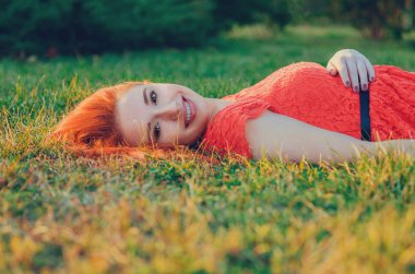 Yaz park gülümseyen içinde çim üzerinde yalan kızıl kafa uzun saçlı genç içerik modeli