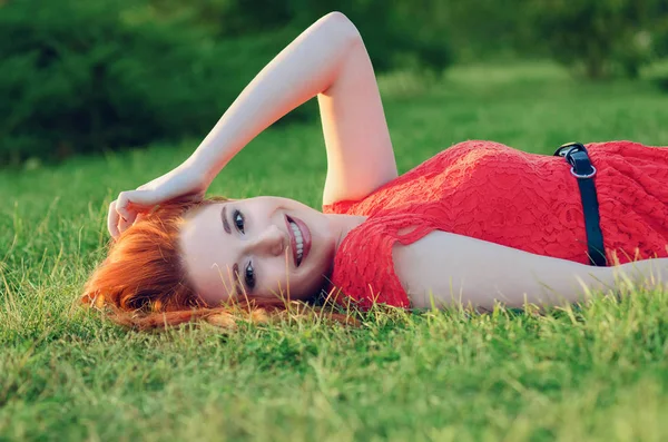 Retrato de una mujer feliz relajada tumbada en la hierba mirando y sonriendo — Foto de Stock