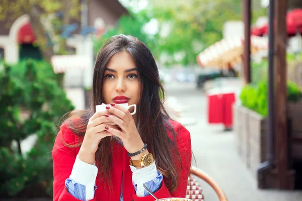 Молода жінка думає тримати каву на модній терасі кафе — стокове фото
