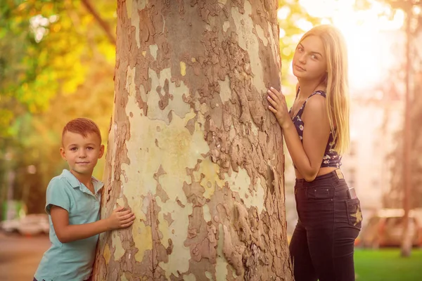 Irmão uma irmã. Menino e adolescente posando perto de um tronco de árvore — Fotografia de Stock