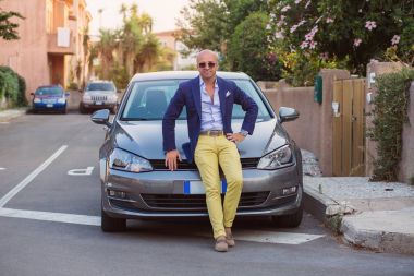 Genç adam arabasında onun lacivert takım elbise ile pozlar