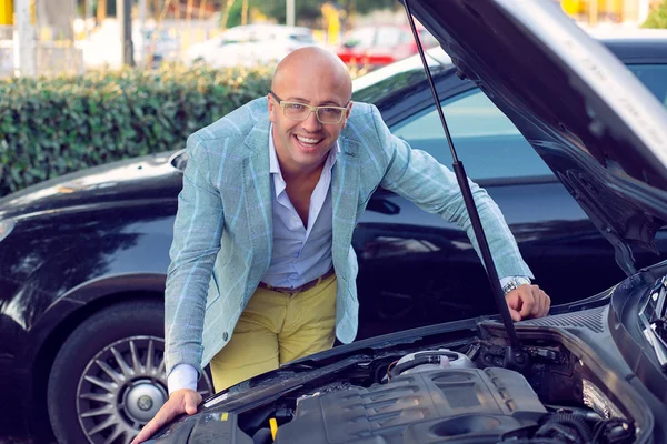 Продавець в дилерській компанії, що показує концепцію карбюратора автомобіля, посміхаючись щасливим — стокове фото