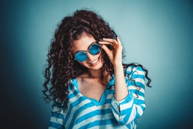 Poz ve gülümseyen güneş gözlüğü ile kıvırcık kadın