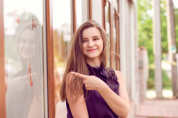 Mulher feliz apontando com o dedo para uma loja de janela — Fotografia de Stock