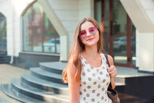 Meisje met lang brunette haar in roze hartvormige zonnebril glimlachend buitenshuis — Stockfoto