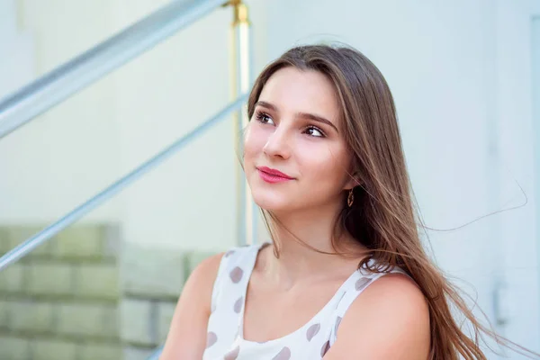 Menina adolescente com cabelos longos sentado em passos olhando para o lado . — Fotografia de Stock