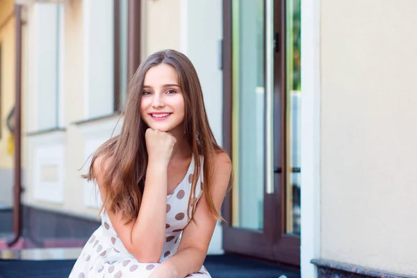 Arckép vidám fiatal nő ül a szabadban, és mosolyogva — Stock Fotó
