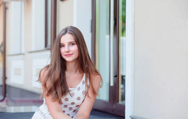 Девочка-подросток с длинными брюнетками сидит на мраморных ступеньках — стоковое фото