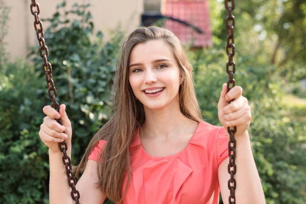 Vrij gelukkig brunette swingende glimlachend vlakbij huis in park op een zonnige dag. — Stockfoto