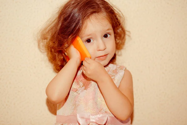 갈색 파스텔 배경에 고립 된 셀룰라 전화를 가진 귀여운 어린 소녀의 초상화 — 스톡 사진