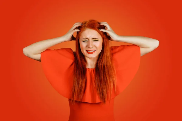 Femme rousse folle effrayée pleurant avec les mains sur la tête isolée sur un fond rouge — Photo