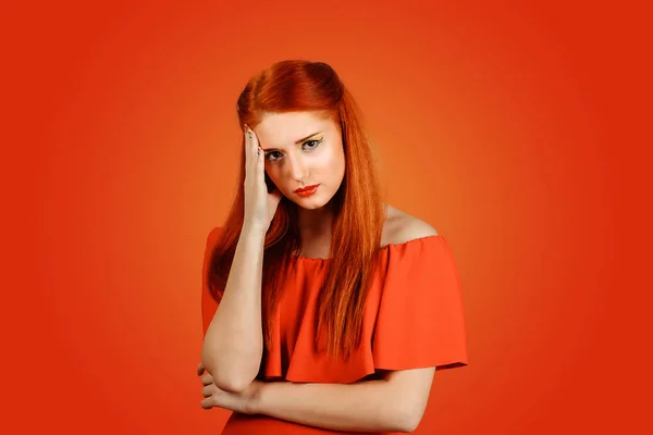 Jong roodharige verdrietig boos vrouw kijken naar u geïsoleerd op rode achtergrond — Stockfoto