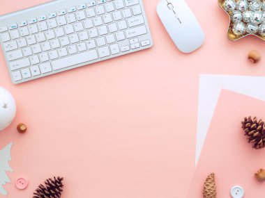 Noel kadın masası boş kağıt notlar, fare, klavye ve kış tatili süslemeleri. Kadınsı blog yazarı kış çalışma alanı. Pembe, şeftali rengi arka planda düz bir görünüm.