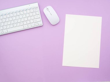 Klavye ve fare ve mor arkaplanda izole edilmiş boş bir kağıt not. Düz konum, üst görünüm kopyalama alanı. Kadınsı iş yeri kavramı.