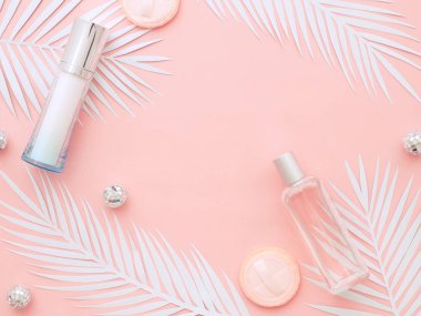 Beyaz eğrelti otu yaprakları, bej ruj, oje, pudra pudrası, parfüm şişesi ve çıplak ten pembe arka planda izole edilmiş Noel topları. Düz konum, üst görünüm kopyalama alanı. Doğal makyaj için kozmetik ürünleri