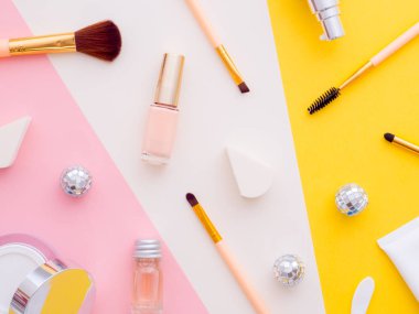 Kadın moda güzellik blogcusu çalışma alanı. Makyaj malzemeleri kozmetik ürünleri, losyonlar, duş jeli şişeleri, sünger, kremler çok renkli pembe beyaz kağıt fotokopi arka planında izole edilmiş. Üst görünüm