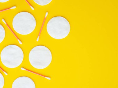 Sarı arkaplandaki pamuklu bez ve pamuklu çubuklar kopyalandı. Yatay görüntü, düz konum, yukarıdan üst görünüm