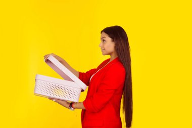 Açık kutu tutan bir kadının yan profili. Sarı arka planda izole edilmiş karışık ırk modeli ve kopyalama alanı. Yatay görüntü. Doğal, makyajsız..