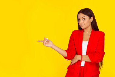 Mutlu güzel kadın, sarı arka planda izole edilmiş boş fotokopi alanını işaret ederek yukarı bakıyor. Olumlu insan yüzü ifadesi duygusu. Karışık ırk modeli Doğal, makyajsız. Yatay resim.