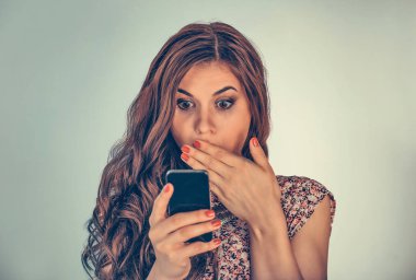 Şok olmuş bir şekilde telefonuna bakan bir kadın. Açık yeşil arka planda izole edilmiş karışık ırk modeli ve kopyalama alanı. Yatay resim.