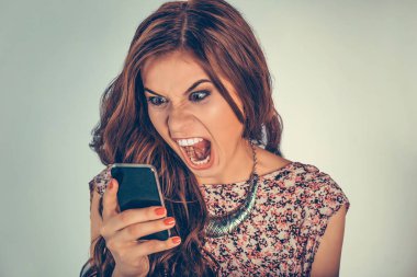 Öfkeyle bağıran bir kadın telefona bakıyor ya da çok kötü bir ses veya viseo mesajı yolluyor. Açık yeşil arka planda izole edilmiş karışık ırk modeli ve kopyalama alanı. Yatay resim.