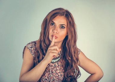 Sessiz bir şekilde el kol hareketi yapan bir kadın, kameraya ciddi ve öfkeyle bakıyor. Açık yeşil arka planda izole edilmiş karışık ırk modeli ve kopyalama alanı. Yatay resim.