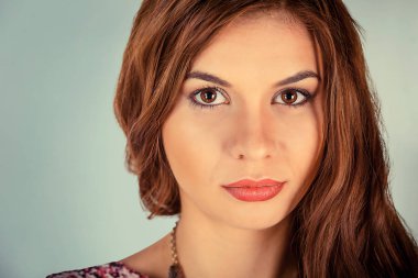 Kamerana ciddi ciddi bakan genç bir kadının ekstra yakın plan portresi. Açık yeşil arka planda izole edilmiş karışık ırk modeli ve kopyalama alanı. Yatay resim.