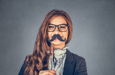 Ciddi bir erkeği taklit eden güzel, güzel, genç bir kadının portresini yakından çek. Gri arka planda izole edilmiş kağıt bıyıklı çekici kız. Olumlu insan duyguları, yüz ifadeleri