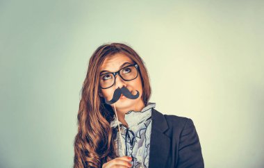 Kafasına yakın bir portre resmi, güzel, genç bir kadın ciddi şüpheci bir adamın bakışlarını taklit ediyor. Yeşil arka planda izole edilmiş kağıt bıyıklı çekici kız. Pozitif duygu ifadesi