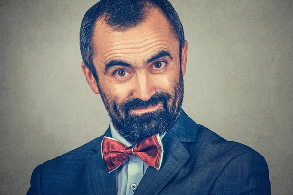 Closeup portrait bearded man looking surprised, wondering to you camera, leaning his head, Face expression, forehead creases. Modern clothes, dark suit, white shirt, red bow, tie. One single person. — 스톡 사진