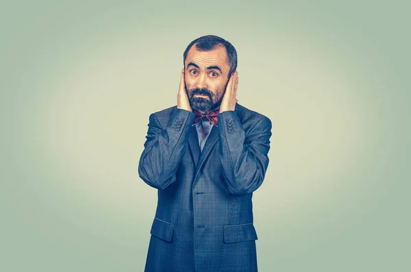 Homem de negócios surpreso e barbudo cobrindo seus ouvidos com palmas das mãos — Fotografia de Stock