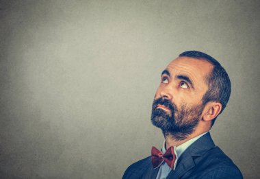 Gri arka planda izole edilmiş bir yere bakmayı düşünen adam.