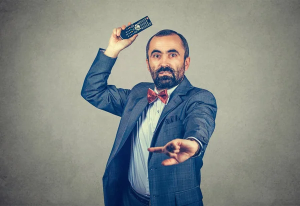 Uzunluğu yarı yarıya olan, uzaktan kumandalı bir adam portresi, korkmuş ve kızgın bir şekilde kameraya bakıyor. Gri arka planda izole edilmiş melez sakallı bir model ve fotokopi alanı. Yatay resim.