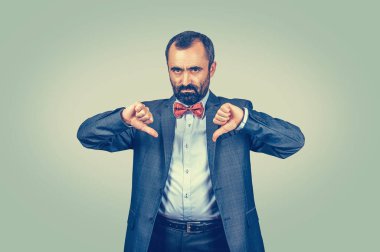 Sinirli, mutsuz, genç adam baş parmak işareti gösteriyor.