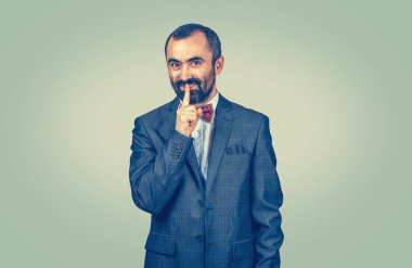 Smiling smug man hipster guy keeps a secret. Confidential information and tips sharing concept. Hipster male with beard in blue jacket white shirt  Isolated on green studio Background. Negative face
