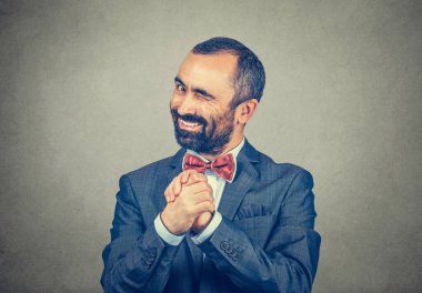 Kind mature businessman showing clasped hands, pretty please winking left eye great deal agreement concept. Mixed race bearded model isolated on green-yellow studio background with copy space 