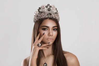 The fashionable sexy woman with smokey eyes makeup showing burgundy color velvet nails posing in studio on white gray background