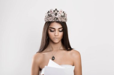 Woman dark beauty queen reading looking attentively a contract, bank statement, tax papers, newspaper documents. Actress miss bride learning her lines text vow isolated white gray background wall